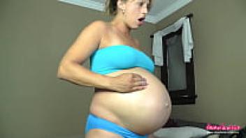 Gorgeous pregnant woman massages and touches her belly.