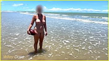 Water splashes a naked wife on a public beach.