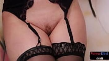 A curvaceous British sex worker observes a sub's cock during a kinky session.